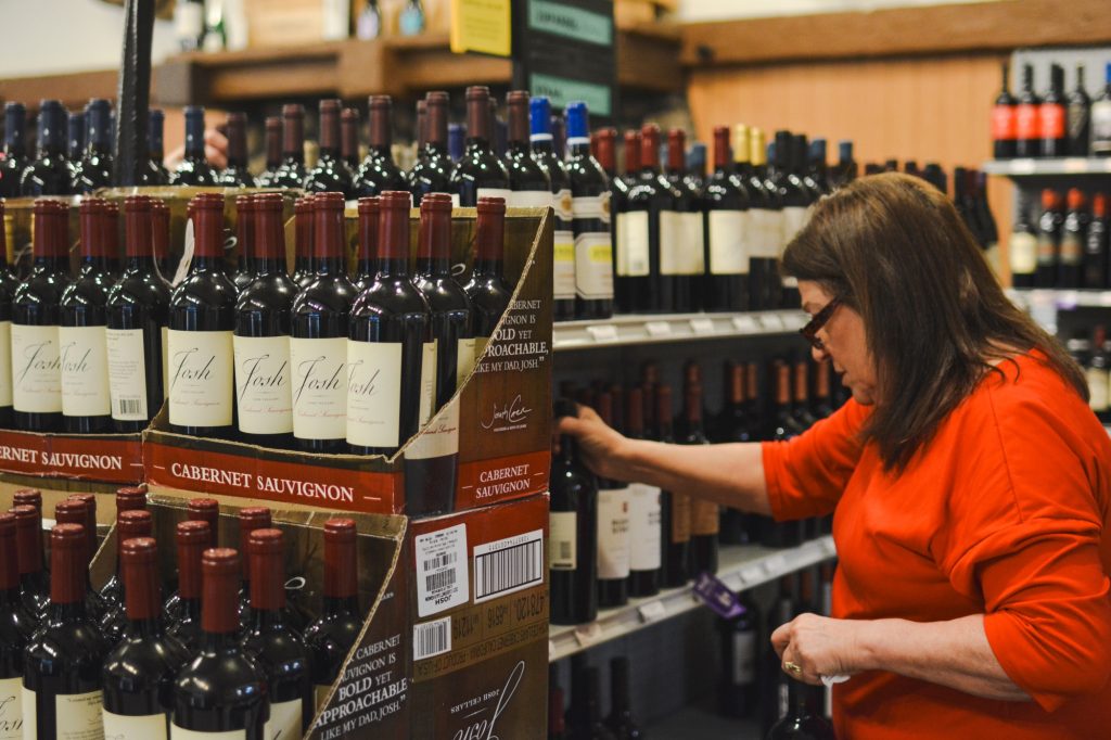 Woman inspecting wine in the wine section at Hickey's Wine & Spirits.