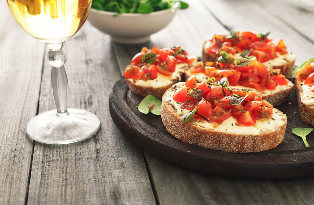 Wine paired with appetizers, white wine with bruschetta with tomatoes goat cheese and basil.
